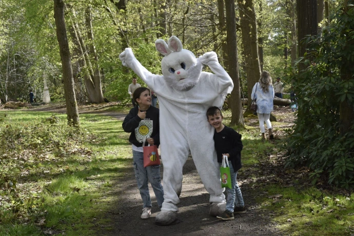 Groep in het bos: Een witte paashaas poseert met een gezin op een pad in het bos.