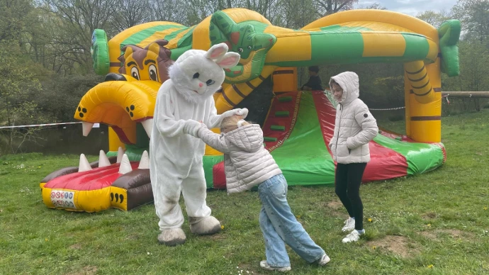 Spelende kinderen: Een kind en een paashaas bij een opblaasbaar springkasteel.